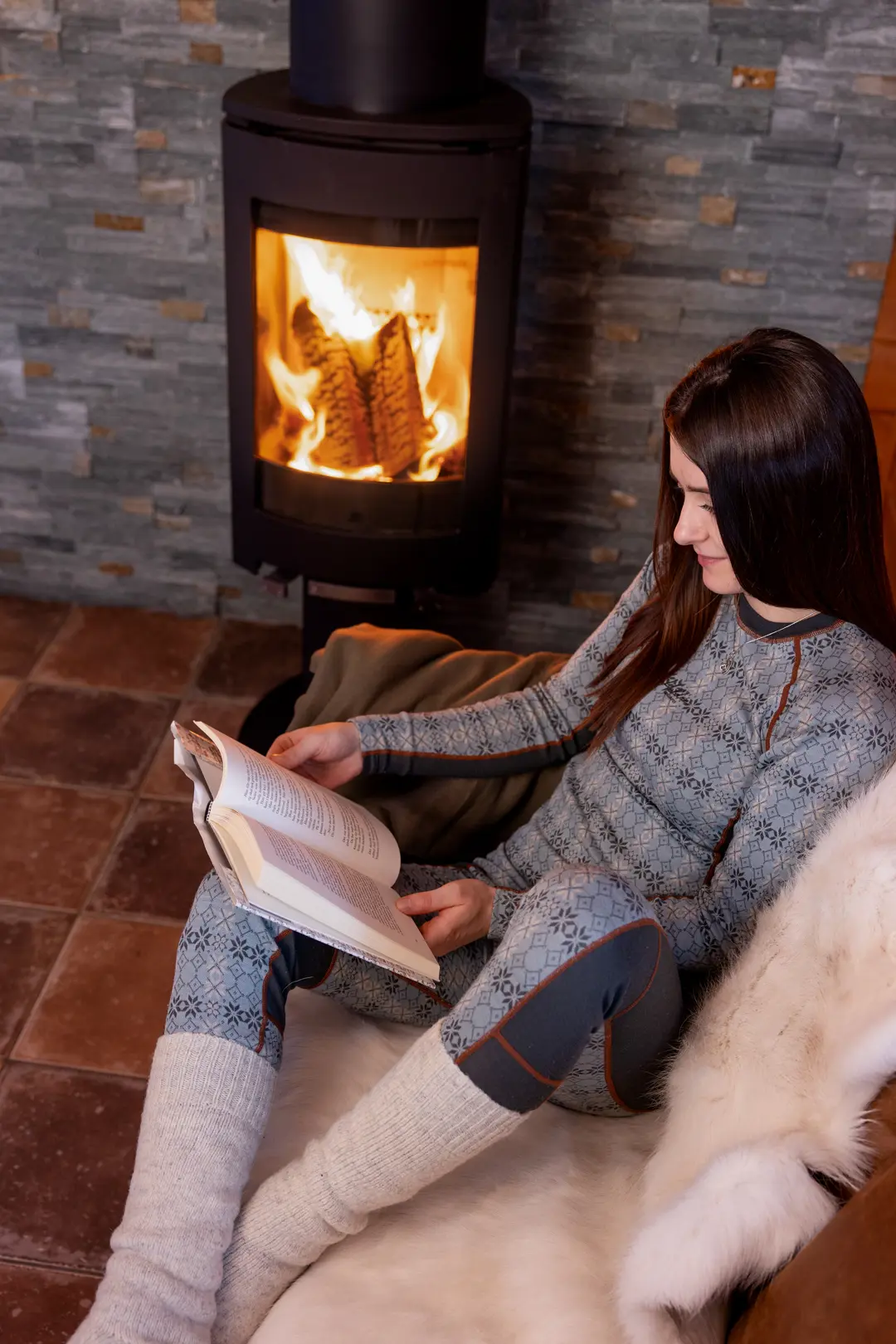 Woman reading a good book by the fireplace in one of the apartments at Filefjellstuene