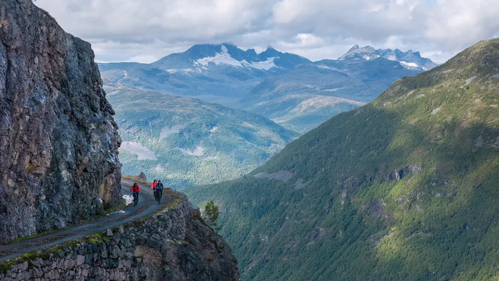 Syklister på Tusenmeteren med fjellene i Hurrungane som bakteppe