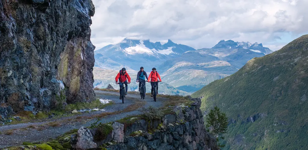 Cyclists on Tusenmeteren with the mountains of Hurrungane as a backdrop
