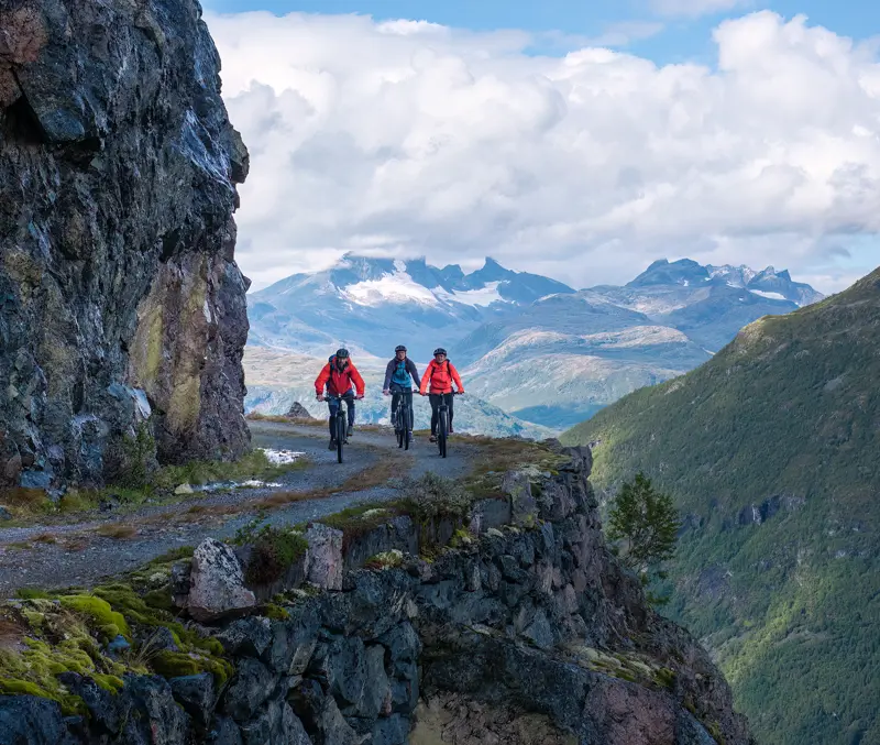 Syklister på Tusenmeteren med fjellene i Hurrungane som bakteppe
