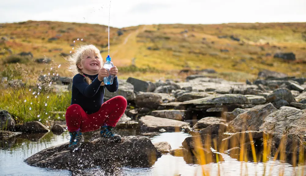 Girl plays with water in a stream on a hike on Kongevegen above Filefjell