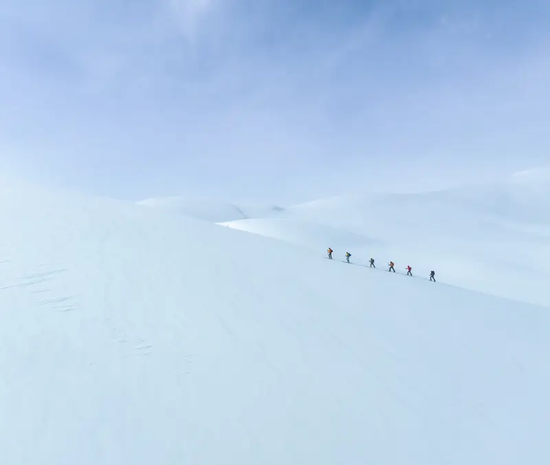 Overview of participants on a randonnée and summit tour course going uphill in a beautiful winter landscape