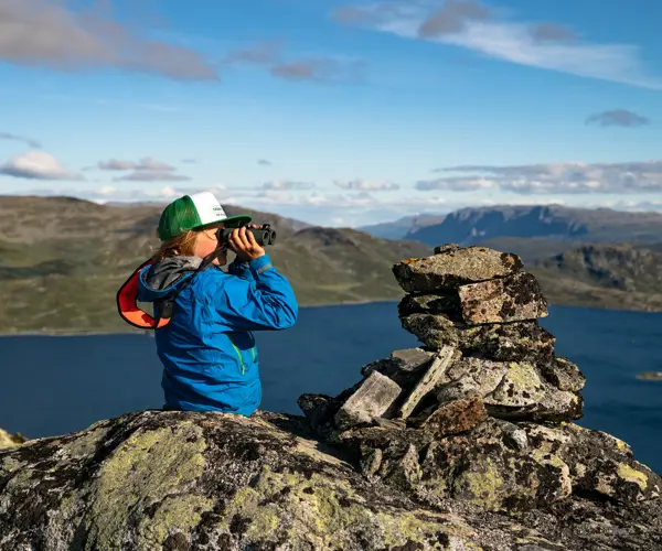 Boy looks through binoculars at the majestic mountains of Jotunheimen