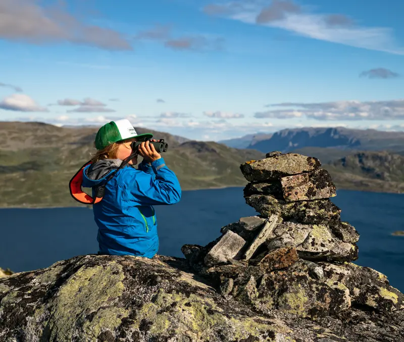Boy looks through binoculars at Jotunheimen's majestic mountains