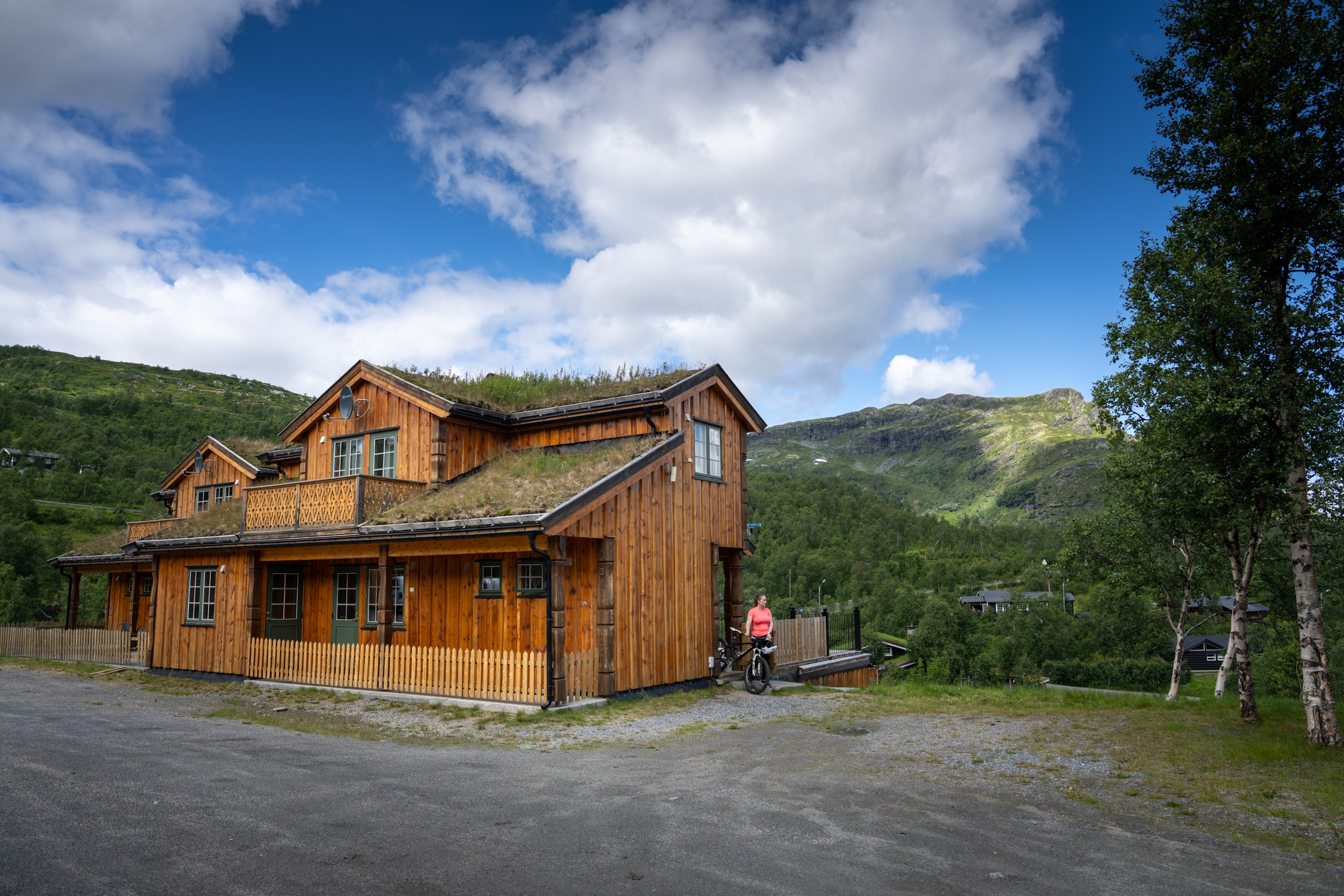 Woman comes out of the apartments at Filefjellstuene with a bicycle