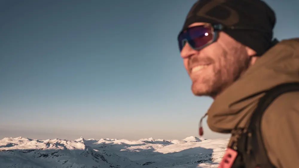 Smiling skier in the winter sun at Tyin Filefjell with a view of Jotunheimen