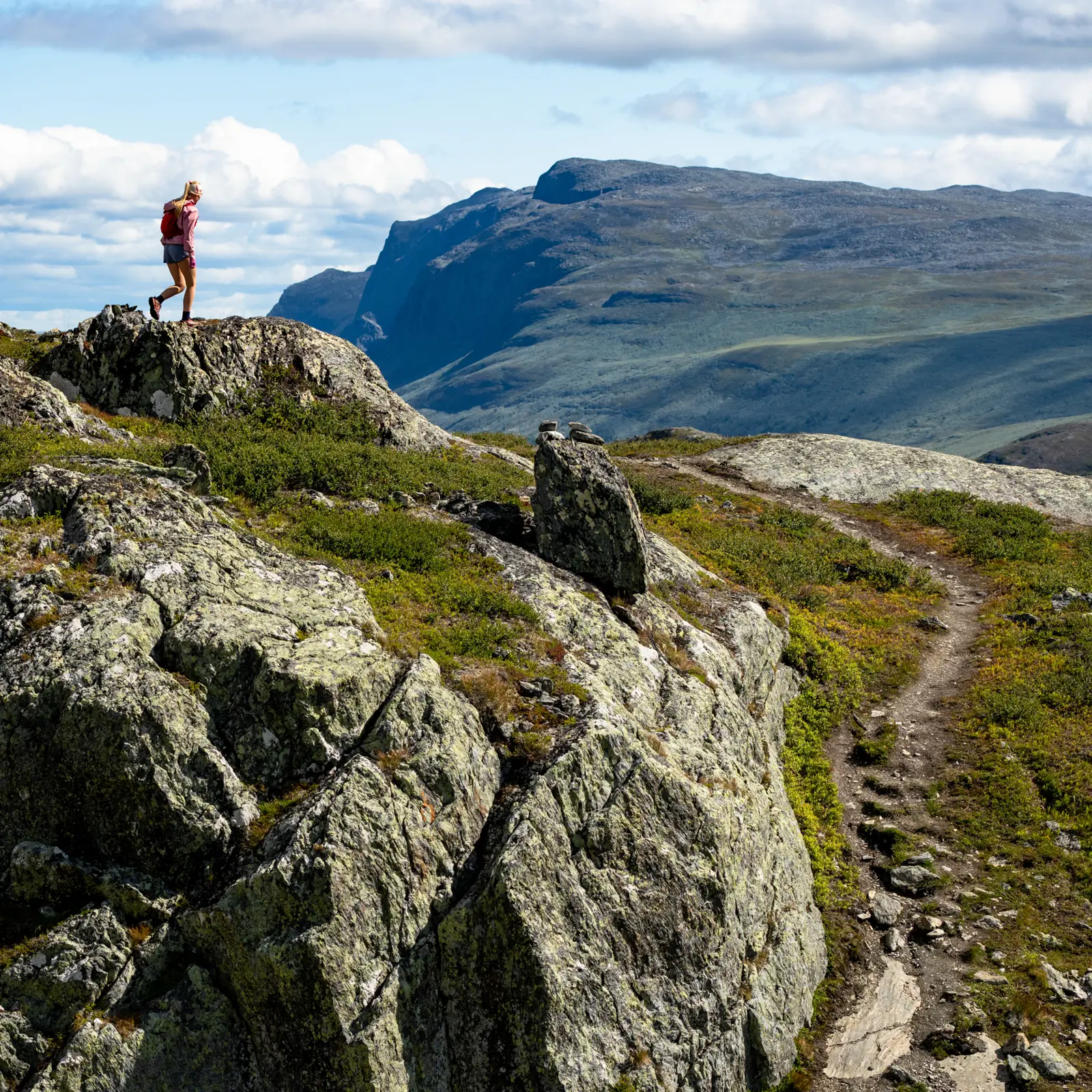 Trail runner in the high mountains – young woman running at Børrenøse