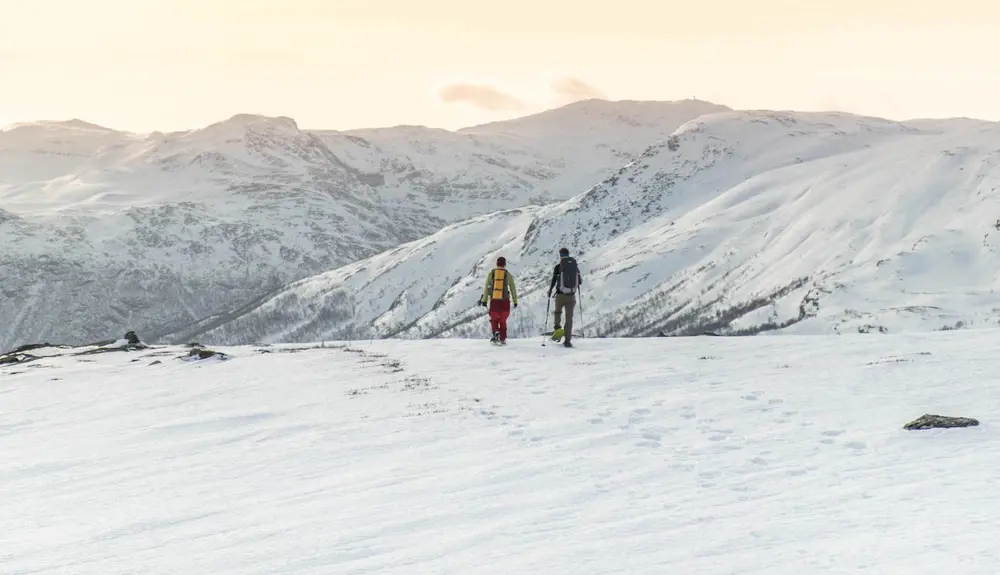 To personer på snesko i smuk aftensol ved Tyin Filefjell