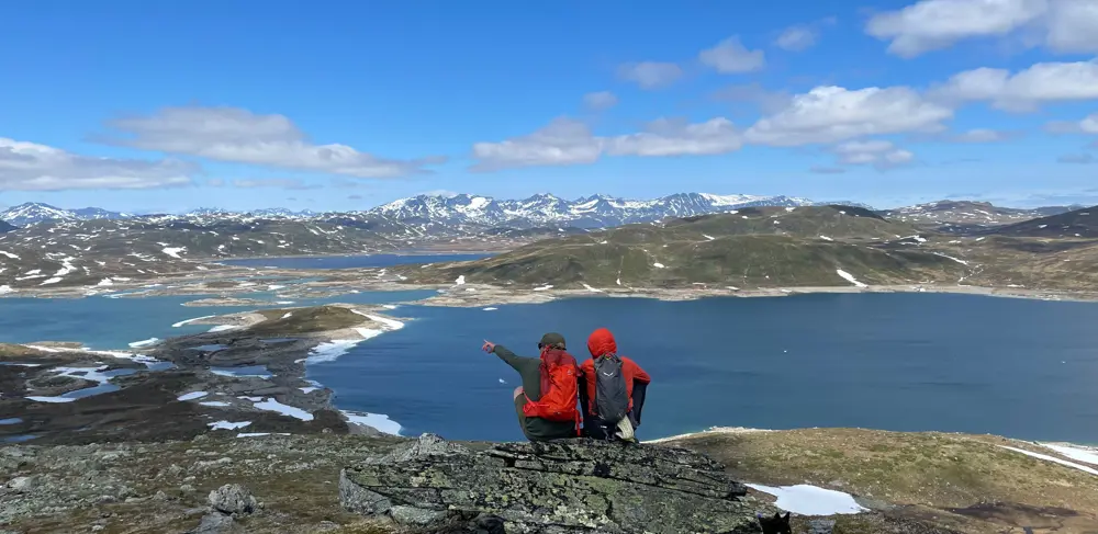 Vandrere nyder udsigten over Jotunheimen på vej til Hødntind