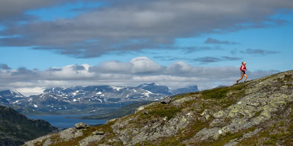 Trailrunner i høyfjellet – ung kvinne løper med Jotunheimen sine majestetiske fjell i bakgrunnen