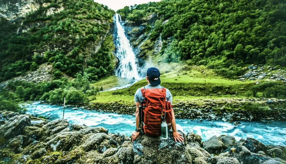 Hiker looking at Vettisfossen waterfall in Utladalen, Årdal