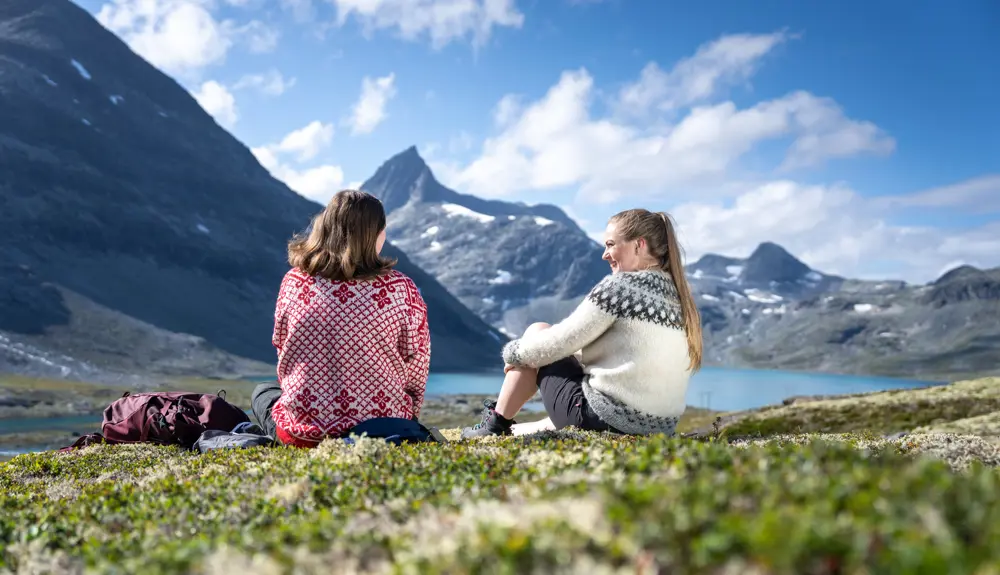 Venner som tar en pause på tur i Koldedalen, men Falketind i bakgrunnen