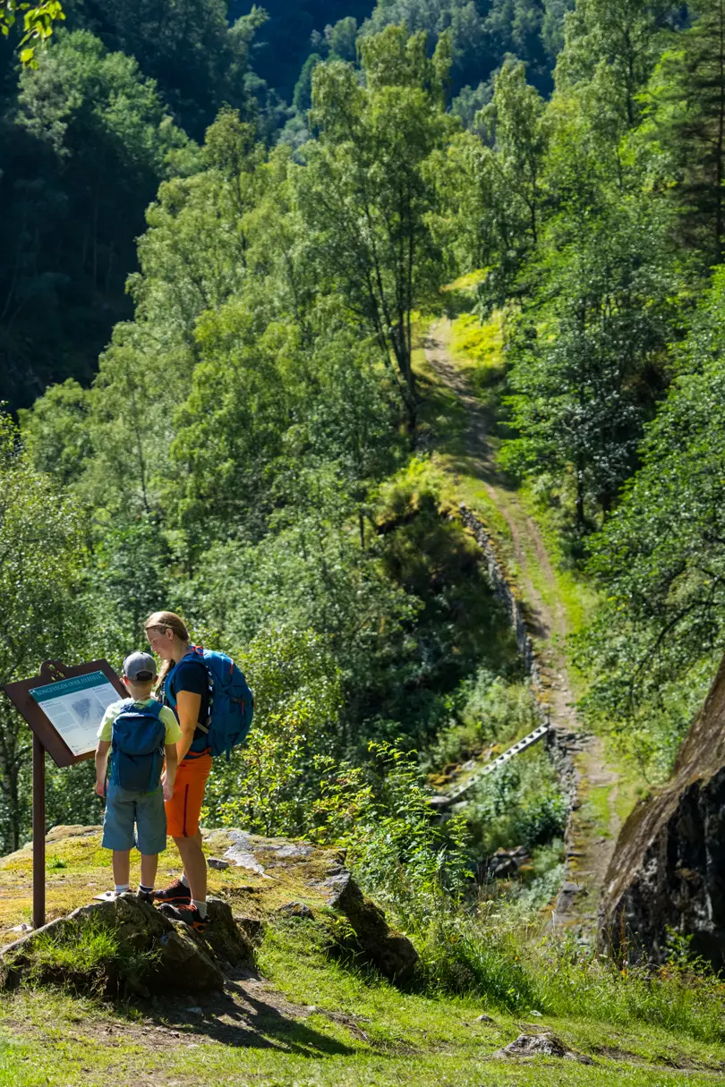 Mor og sønn leser informasjonstavle på tur på historiske Kongevegen