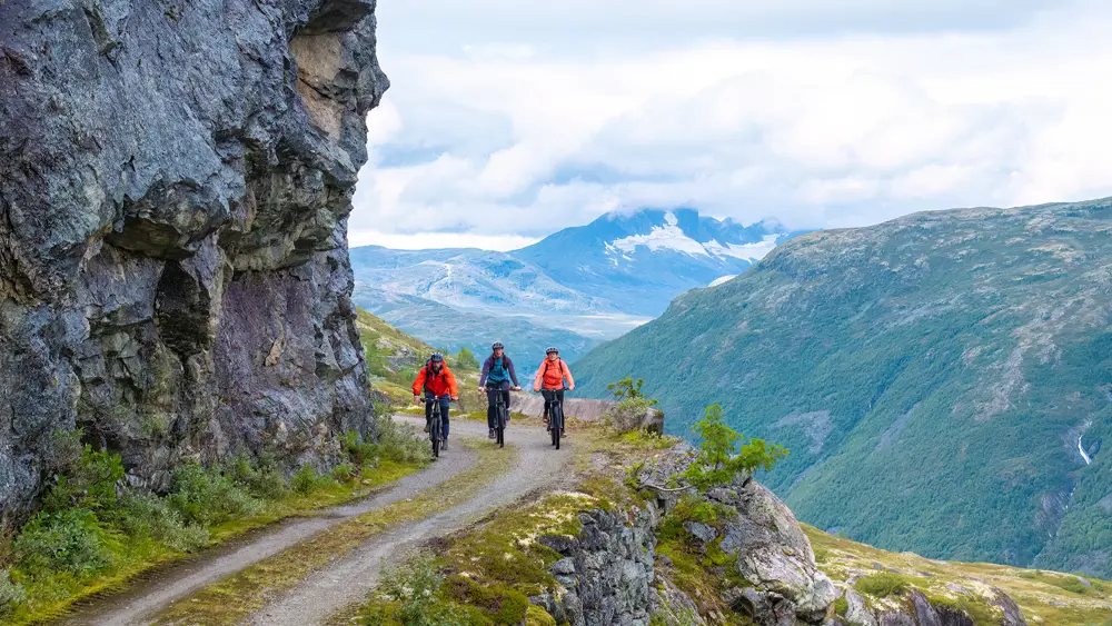 Cyclists on Tusenmeteren with the mountains of Hurrungane as a backdrop