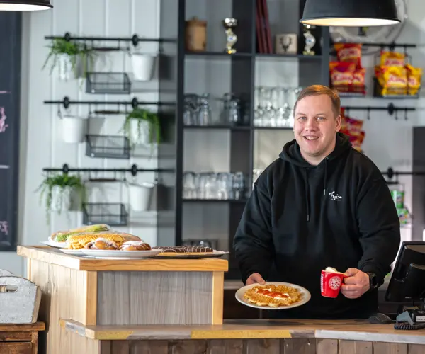 Tjeneren serverer vafler og kakao med fløde i Ski Cafe i Tyin Filefjell Skicenter