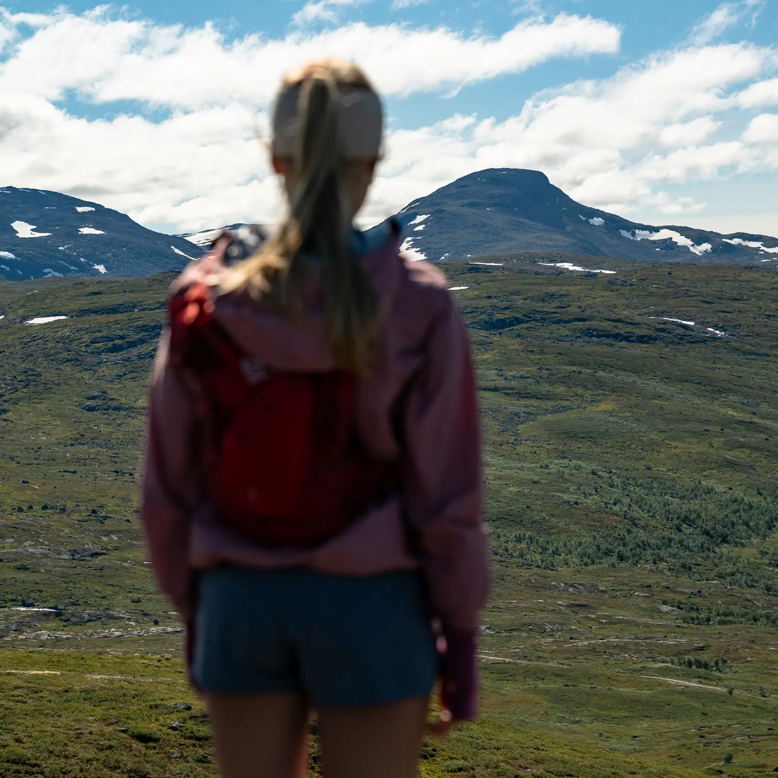 Trailrunner i høyfjellet – ung kvinne sre på utsikten mot Suletinden