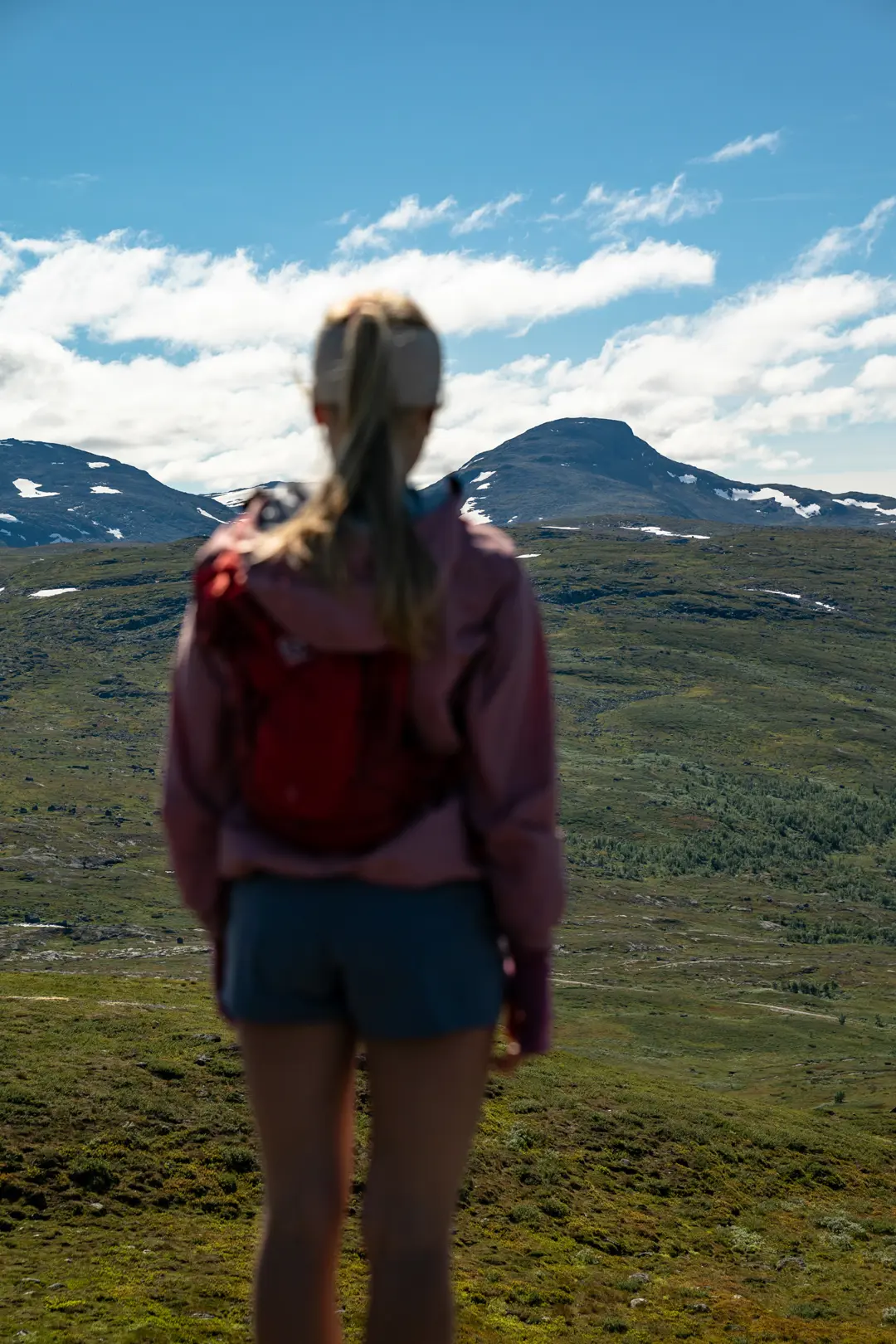 Trail runner in the high mountains – young woman enjoys the view towards Suletinden