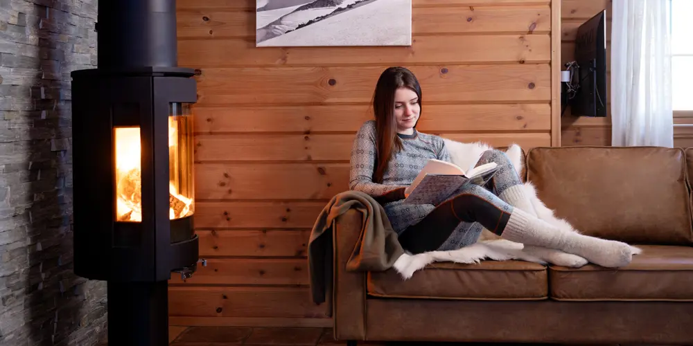 Kvinne leser en god bok ved peisen i en av leilighetene på Filefjellstuene