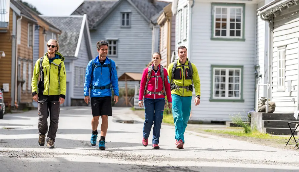 Hikers on The King's Road walk among the traditional wooden houses in Lærdalsøyri